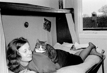 831891 Afbeelding van Ilona van der Linden, liggend op bed in het huis Ondiep 67bis te Utrecht, met een tevreden kat op ...